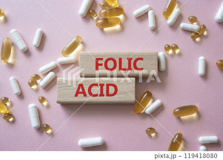 Folic acid symbol. Wooden blocks with words Folic acid. Beautiful pink background with pills. Medicine and Folic acid concept. Copy space. Folic acid symbol. Wooden blocks with words Folic acid. Beautiful pink background with pills. Medicine and Folic acid concept. Copy space. 119418080