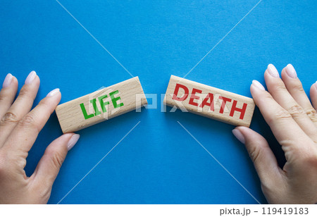 Life or Death symbol. Concept word Life or Death on wooden blocks. Businessman hand. Beautiful blue background. Business and Life or Death concept. Copy space Life or Death symbol. Concept word Life or Death on wooden blocks. Businessman hand. Beautiful blue background. Business and Life or Death concept. Copy space 119419183
