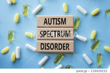 Autism Spectrum Disorder symbol. Concept word Autism Spectrum Disorder on wooden blocks. Beautiful blue background with pills. Medicine and Autism Spectrum Disorder concept. Copy space 119420252