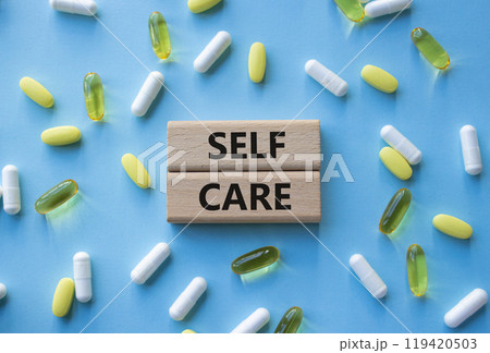 Self Care symbol. Concept word Self Care on wooden blocks. Beautiful blue background with pills. Business and Self Care concept. Copy space 119420503