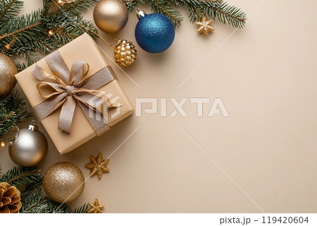 Commemorate New Year in elegance. Top view perspective of carefully wrapped giftbox, chic tree ornaments, glittery balls, seasonal adornments on beige backdrop Commemorate New Year in elegance. Top view perspective of carefully wrapped giftbox, chic tree ornaments, glittery balls, seasonal adornments on beige backdrop 119420604