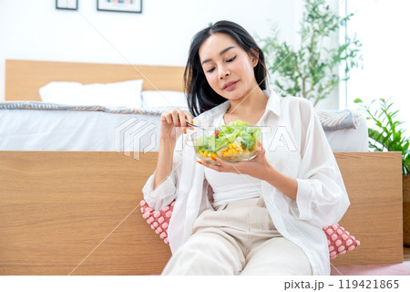 Pretty Asian woman hold bowl of vegetable salad and she express happy with eating. Pretty Asian woman hold bowl of vegetable salad and she express happy with eating. 119421865