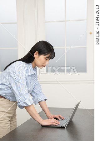 デスクのノートパソコンを立って操作する女性 デスクのノートパソコンを立って操作する女性 119422613