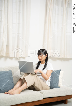 リビングのソファーでパソコンを使う女性 リビングのソファーでパソコンを使う女性 119422657