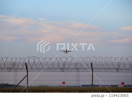 A Passenger Plane Is Taking Off Over A Fenced Airport Runway 119423003