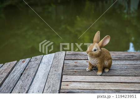 Rabbit model decor at wooden bridge by pond with tree reflection 119423951