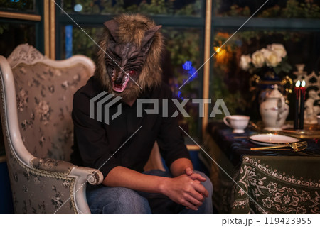 Asian man with werewolf mask at table for 2024 Halloween party 119423955