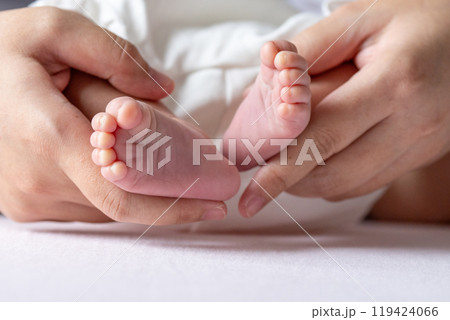A mother gentle hands cradle her baby tiny feet, capturing a tender moment of warmth and love, with soft, delicate toes resting in her caring embrace. A mother gentle hands cradle her baby tiny feet, capturing a tender moment of warmth and love, with soft, delicate toes resting in her caring embrace. 119424066