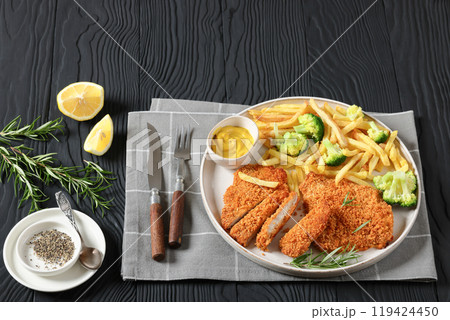 breaded pork cutlet with fries, broccoli on plate 119424450