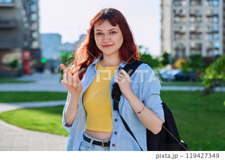 Young smiling red-haired hipster female with facial piercing looking at camera outdoor Young smiling red-haired hipster female with facial piercing looking at camera outdoor 119427349