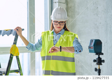 Technical profession woman in protective vest helmet working on construction Technical profession woman in protective vest helmet working on construction 119427555