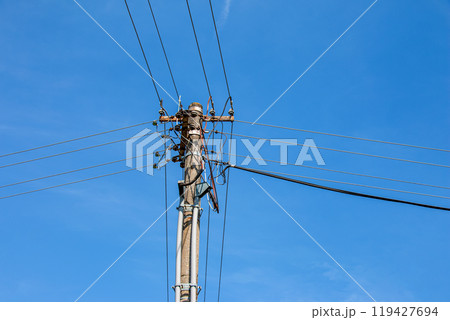 Electric pole power lines outgoing electric wires againts on cloud blue sky. 119427694