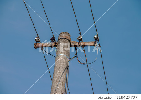 Electric pole power lines outgoing electric wires againts on cloud blue sky. 119427707