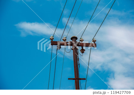 Electric pole power lines outgoing electric wires againts on cloud blue sky. 119427709