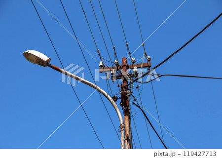Electric pole power lines outgoing electric wires againts on cloud blue sky. 119427713