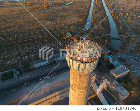 Construction site of a power plant a high chimney.Dangerous work at height.A renovation is smokestack.Contractor repairing a chimney at a highrise.Workers in a hard hat.Dangerous work at the daytime. Construction site of a power plant a high chimney.Dangerous work at height.A renovation is smokestack.Contractor repairing a chimney at a highrise.Workers in a hard hat.Dangerous work at the daytime. 119431846