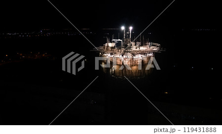 Illuminated construction site at dusk.Dangerous work at the nighttime.Workers build a tall chimney for a plant.Construction process.Contractor renovation is smokestack on highrise.Worker in hardhat Illuminated construction site at dusk.Dangerous work at the nighttime.Workers build a tall chimney for a plant.Construction process.Contractor renovation is smokestack on highrise.Worker in hardhat 119431888