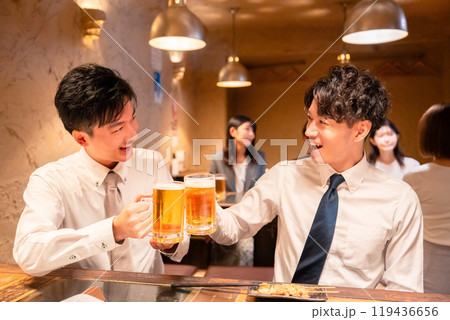 居酒屋でビールを飲む二人の若手ビジネスマン 119436656