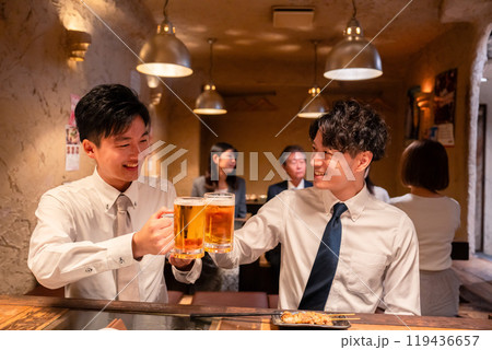 居酒屋でビールを飲む二人の若手ビジネスマン 119436657