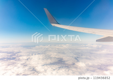 View from the airplane window at a beautiful cloudy sky and the airplane wing 119436852