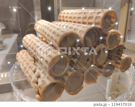 Waffle rolls with condensed milk cream lie in a pile in the window of a cafe store Waffle rolls with condensed milk cream lie in a pile in the window of a cafe store 119437019