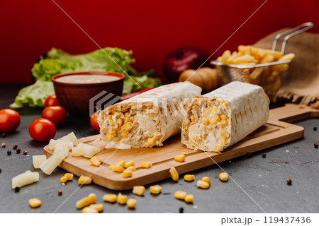 Juicy BBQ chicken wrap with corn filling, cut and styled on board. Ideal for fast-food lovers 119437436