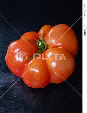 Vertical macro photo of a freshly harvested tomatoin black background. 119437862