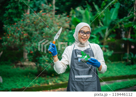 hijab asian woman holding recycled plastic bottle and garden trowel 119446112