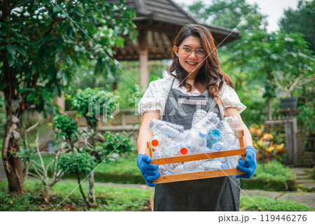 asian woman wearing apron holding plastic bottle in wooden storage asian woman wearing apron holding plastic bottle in wooden storage 119446276
