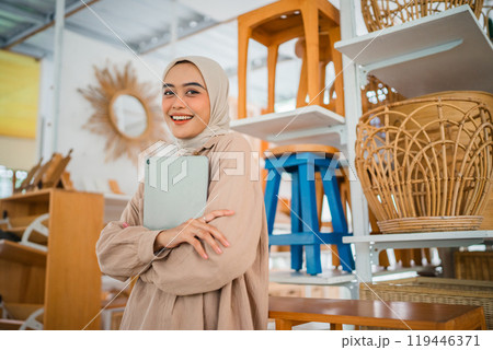 A Smiling Woman Holding a Notebook in a Stylishly Decorated Furniture Store A Smiling Woman Holding a Notebook in a Stylishly Decorated Furniture Store 119446371