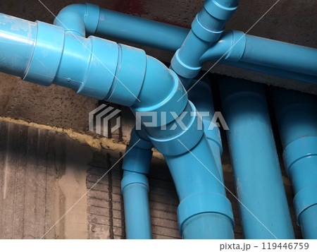 A bright blue pipes attached to a solid concrete wall A bright blue pipes attached to a solid concrete wall 119446759