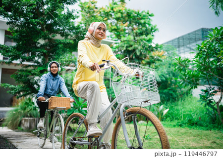 young veiled woman with headphones on a bicycle with friends cycling 119446797