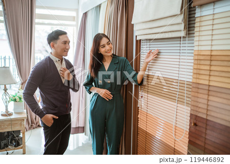 beautiful asian shopkeeper showing the blinds sample to the male customer beautiful asian shopkeeper showing the blinds sample to the male customer 119446892
