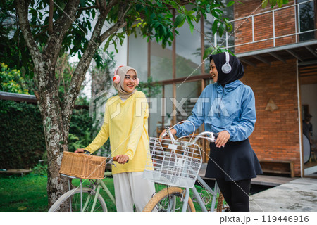 Two Women Happily Enjoying a Relaxing Day Out Riding Bicycles in a Serene Environment 119446916