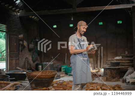 Smiling Chef in Rustic Kitchen Using Tablet for Recipe Management and Organization 119446999