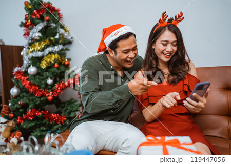 A Joyful Couple is Celebrating Christmas Together with Gifts and a Mobile Phone 119447056