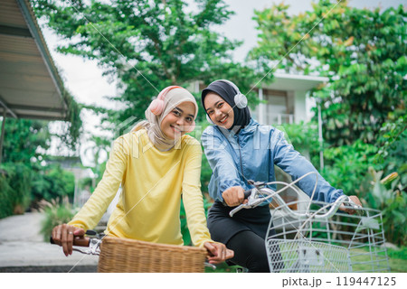 two beautiful Muslim women wearing headphones on a morning bike ride 119447125