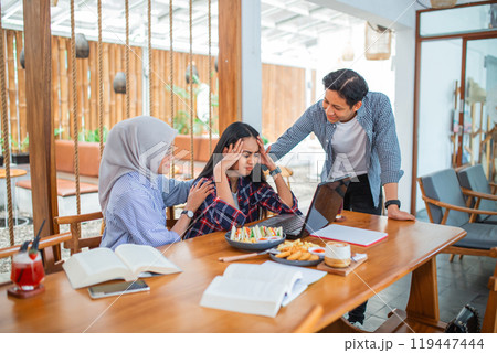 Young woman with a headache sitting using a laptop computer with two friends 119447444