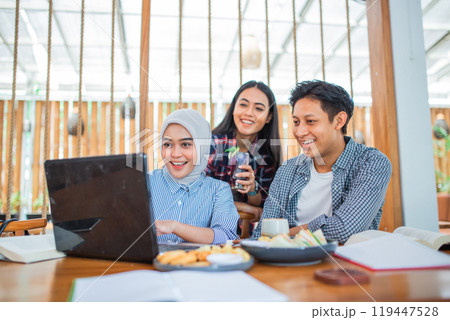 three young men and women looking at a laptop together three young men and women looking at a laptop together 119447528