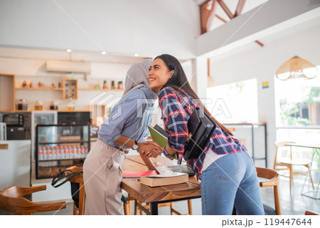 young Indonesian businesswoman kissing on both cheeks while meeting young Indonesian businesswoman kissing on both cheeks while meeting 119447644