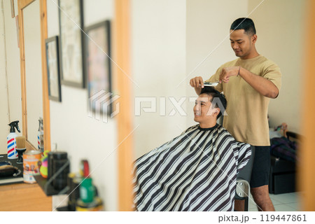 A man is currently having his hair cut by a skilled barber in a barber shop 119447861