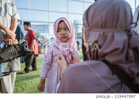 A child dressed in traditional attire interacts joyfully with an adult outdoors 119447997