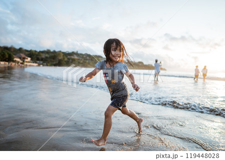 A Joyful Child Happily Running Along the Beach at Sunset, Embracing Freedom 119448028