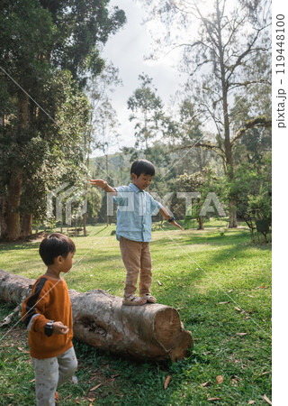 Children Enjoying the Great Outdoors Balancing on a Log in the Park for Fun Children Enjoying the Great Outdoors Balancing on a Log in the Park for Fun 119448100