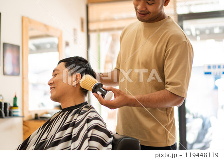 A man is currently having his hair cut by a barber inside a barber shop A man is currently having his hair cut by a barber inside a barber shop 119448119