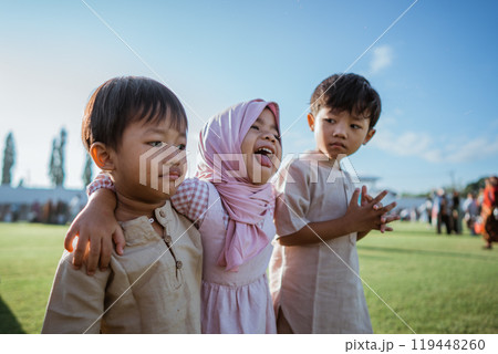 Happy children from diverse backgrounds celebrating outdoors in traditional attire 119448260