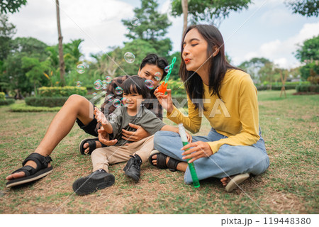 mom sits with her son and father as they play making bubbles 119448380