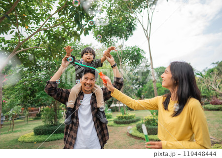 mom makes bubbles with a boy on his father's shoulders while playing mom makes bubbles with a boy on his father's shoulders while playing 119448444