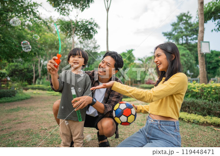 a boy playing bubbles with mom and dad on vacation a boy playing bubbles with mom and dad on vacation 119448471