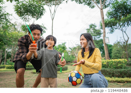 A father, mother and son play bubbles and balls in the park 119448486